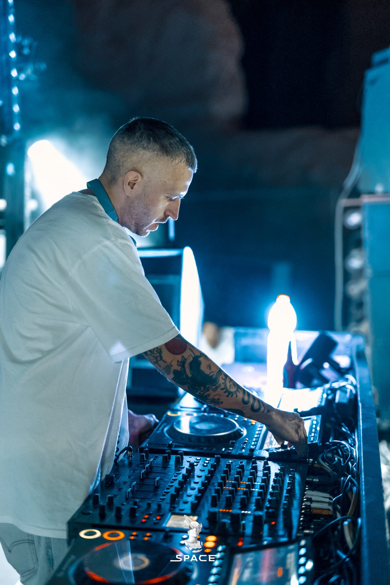 A DJ at the decks under blue light at a SPACE night event